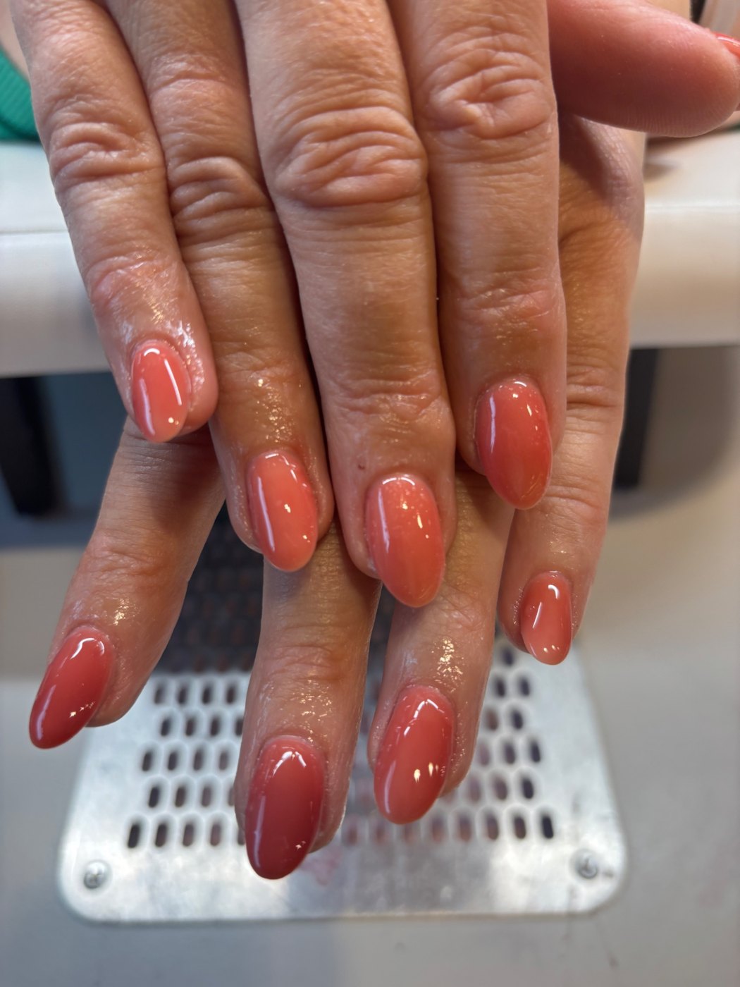 Glanzende koraalroze gellak op afgeronde nagels