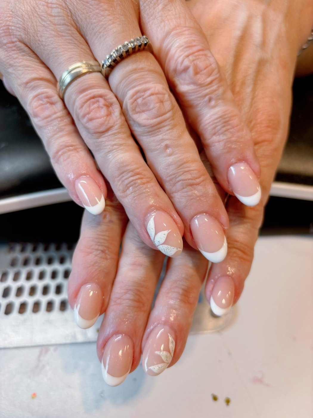Franse manicure met witte bloemblaadjes en glitter accenten